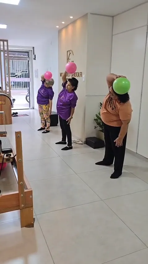 Atividade em grupo com movimentos dos braços e uso de bolas.